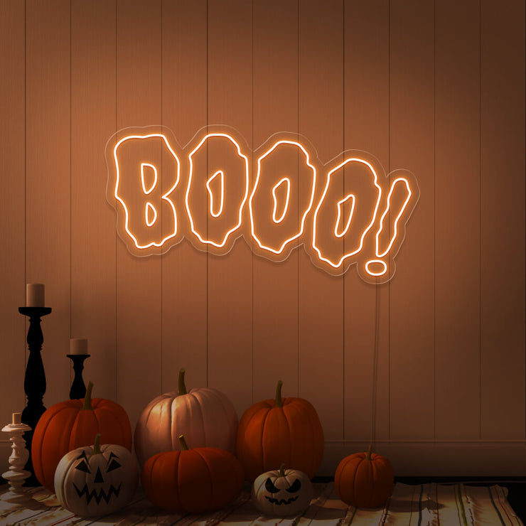 orange boo neon sign with halloween pumpkins on floor