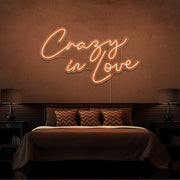 orange crazy in love neon sign hanging on bedroom wall
