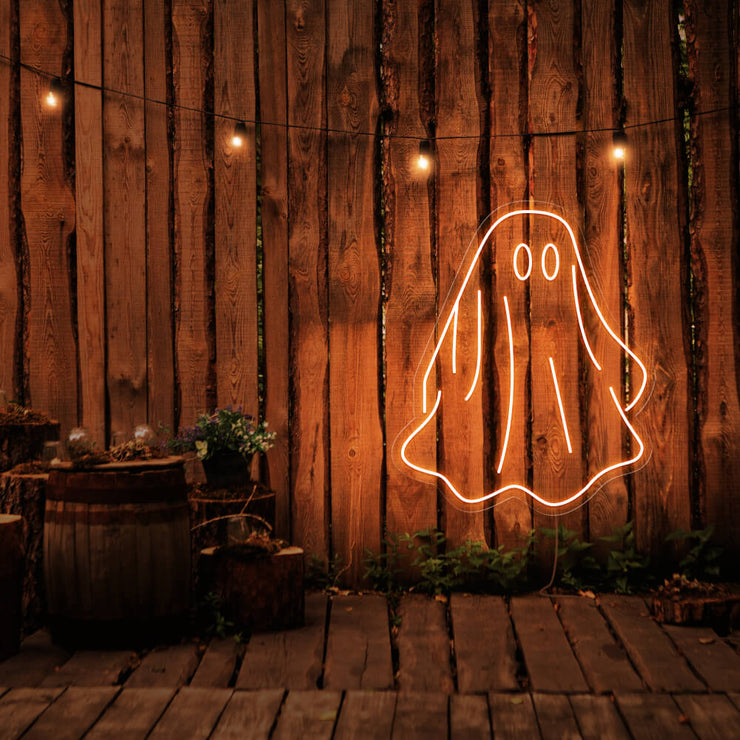 orange draped ghost neon sign hanging on timber wall