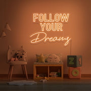 orange follow your dreams neon sign hanging on kids bedroom wall