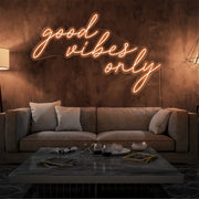 orange good vibes only neon sign hanging on living room wall