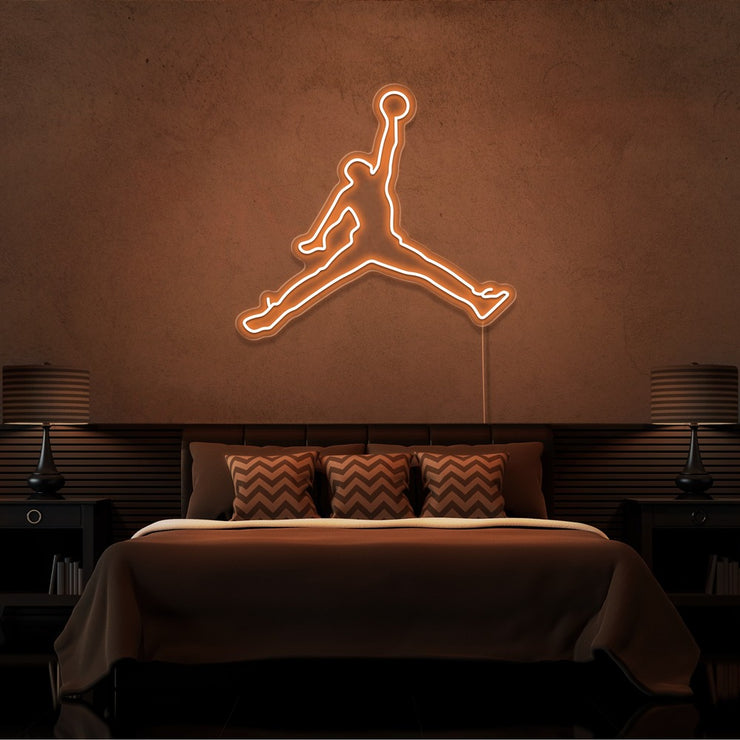 orange jordan jumpman neon sign hanging on bedroom wall
