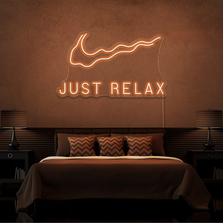 orange just relax neon sign hanging on bedroom wall