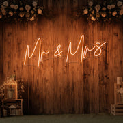 orange mr and mrs neon sign hanging on wall with flowers