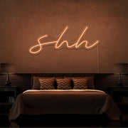 orange shh neon sign hanging on bedroom wall