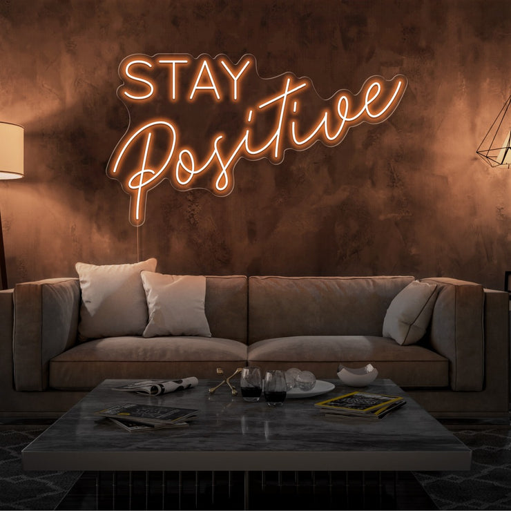 orange stay positive neon sign hanging on living room wall