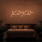 orange xoxo neon sign hanging on bedroom wall