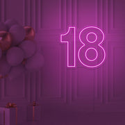 hot pink 18 neon sign hanging on wall with balloons