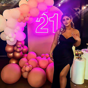 girl standing in front of hot pink 21 neon sign with balloon backdrop