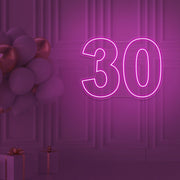 hot pink 30 neon sign hanging on wall with balloons