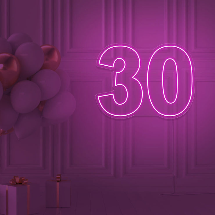 hot pink 30 neon sign hanging on wall with balloons
