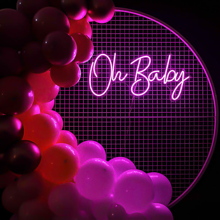 pink oh baby neon sign hanging on white mesh backdrop frame with balloons