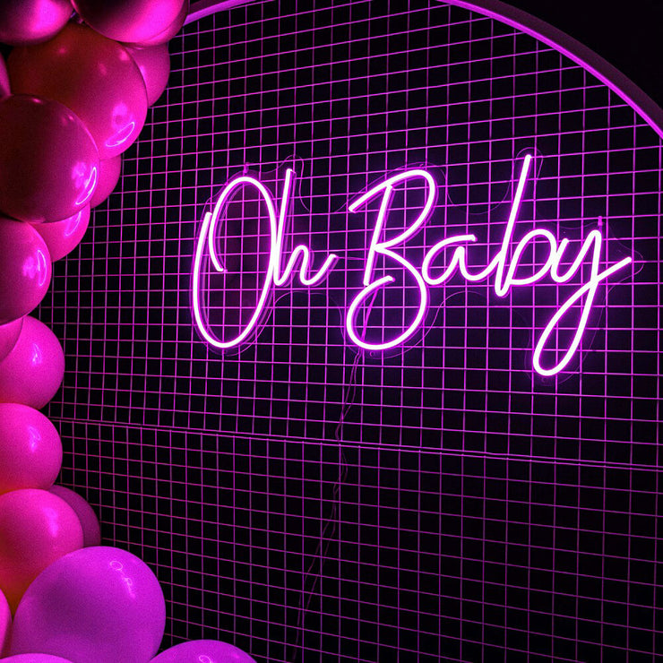 pink oh baby neon sign hanging on white mesh backdrop frame