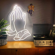 praying hands neon sign hanging on wall