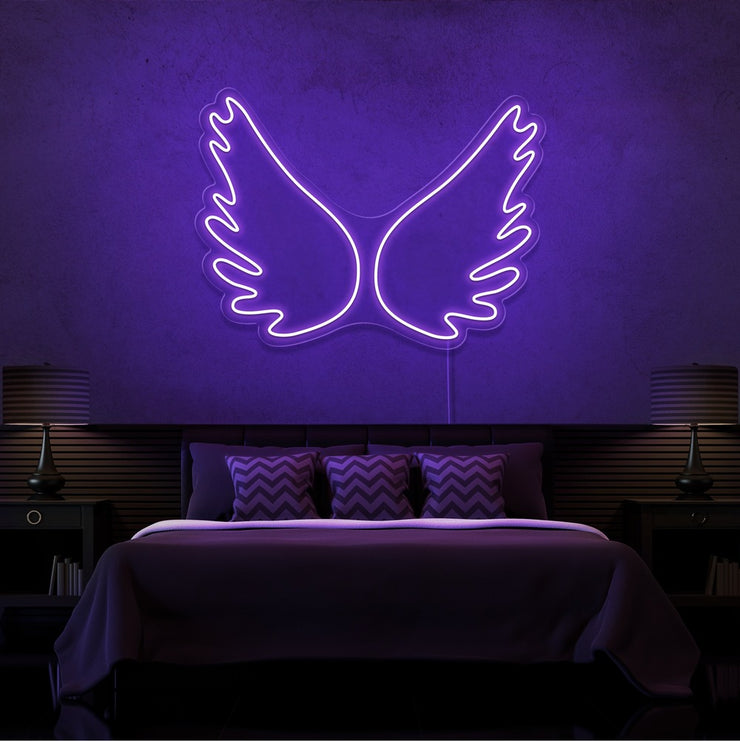 purple angel wings neon sign hanging on bedroom wall