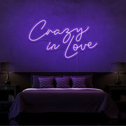 purple crazy in love neon sign hanging on bedroom wall