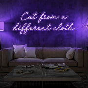 purple cut from a different cloth neon sign hanging on living room wall