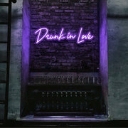 purple drunk in love neon sign hanging on bar wall
