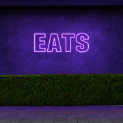 purple eats neon sign hanging on outside wall