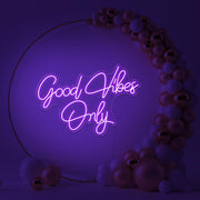 purple good vibes only neon sign hanging inside balloon hoop backdrop