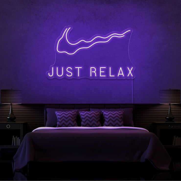 purple just relax neon sign hanging on bedroom wall