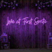 purple love at first spritz neon sign hanging on timber wall