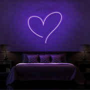 purple love heart neon sign hanging on bedroom wall