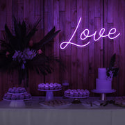 purple love neon sign hanging on timber wall above dessert table