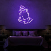 purple praying hands neon sign hanging on bedroom wall