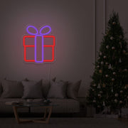 purple Christmas present neon sign hanging on lounge room wall next to Christmas tree