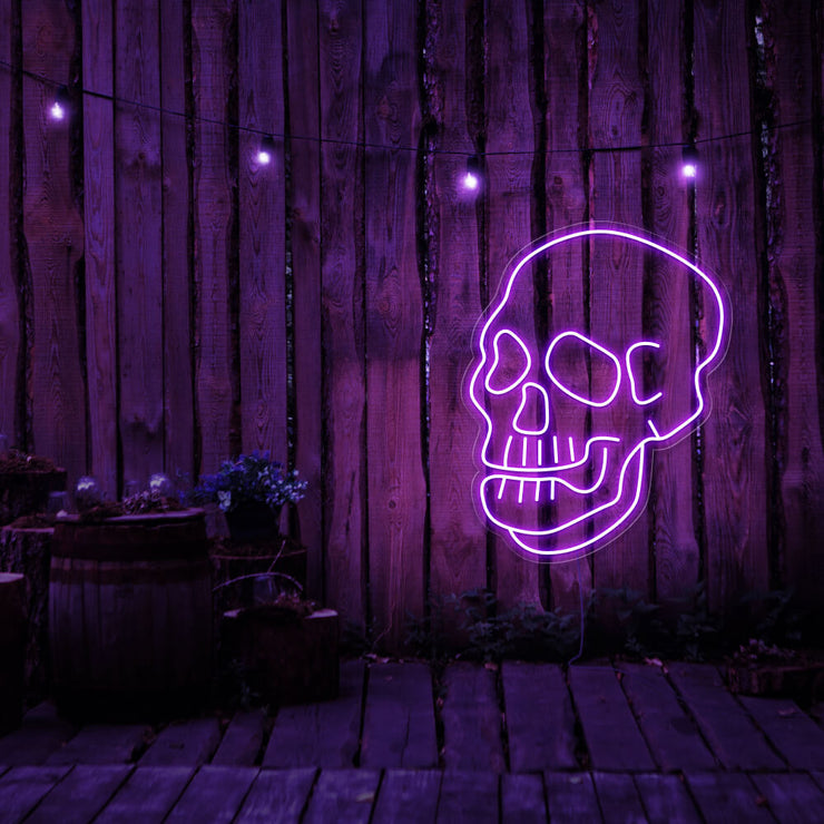 purple skull neon sign hanging on timber fence