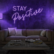 purple stay positive neon sign hanging on living room wall