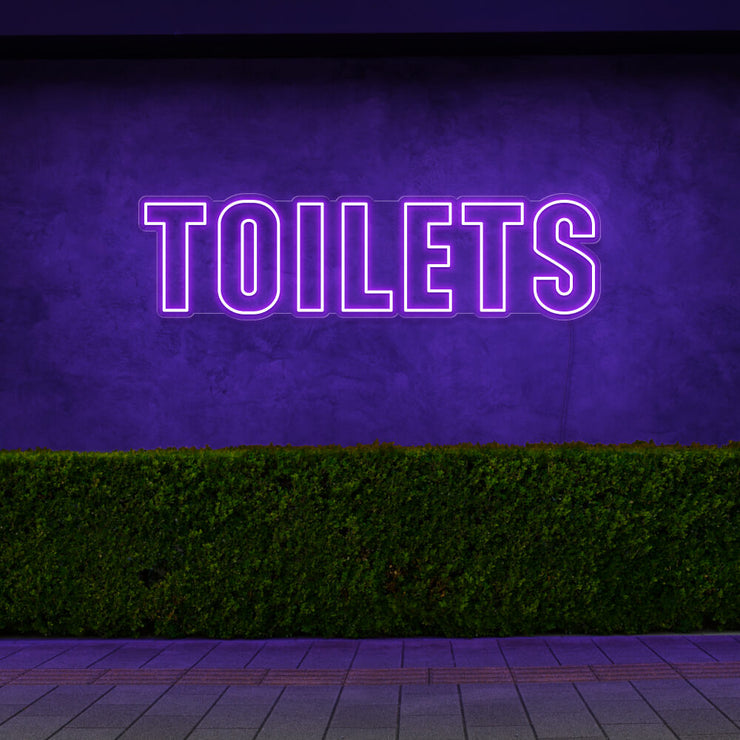 purple toilets neon sign hanging on outdoor wall