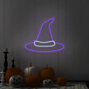 purple witch hat neon sign hanging on wall above pumpkins