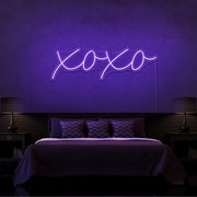 purple xoxo neon sign hanging on bedroom wall