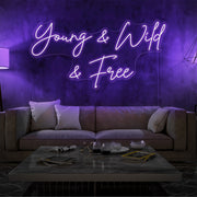 purple young and wild and free neon sign hanging  on living room wall