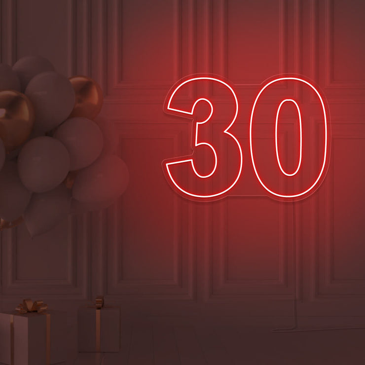 red 30 neon sign hanging on wall with balloons