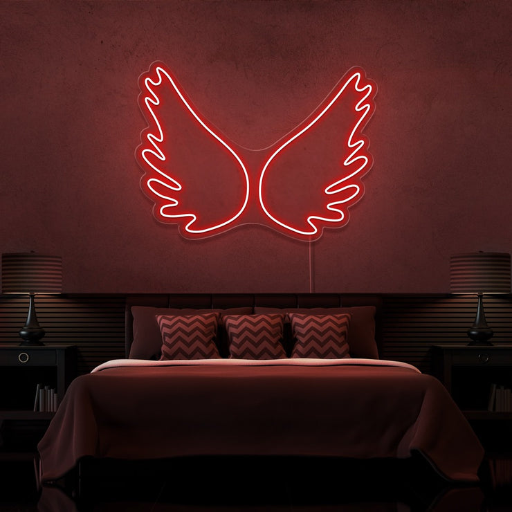 red angel wings neon sign hanging on bedroom wall