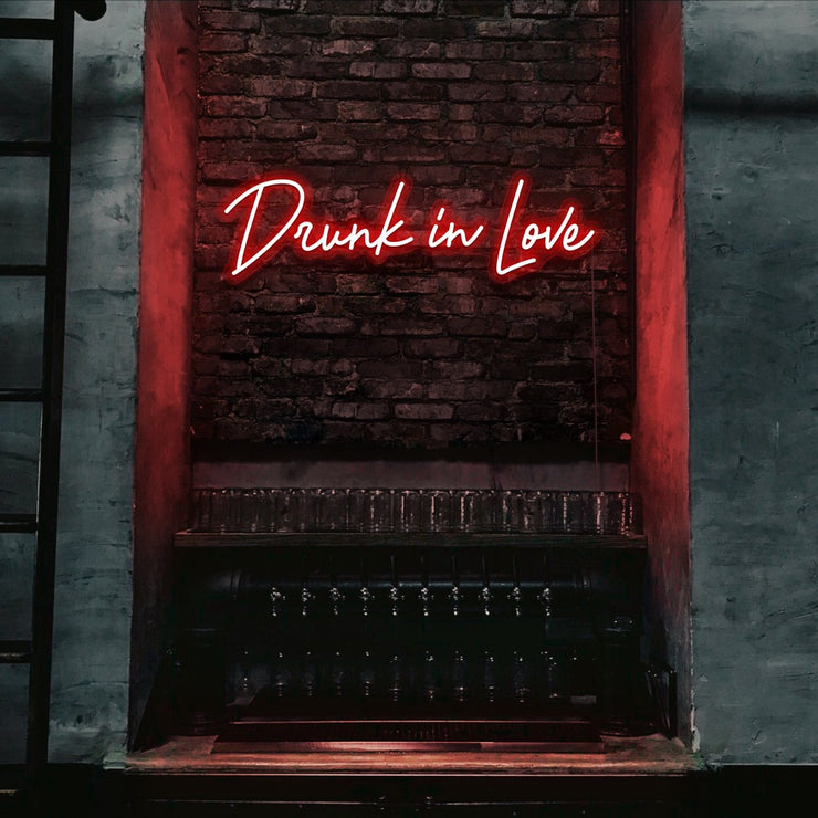 red drunk in love neon sign hanging on bar wall