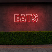 red eats neon sign hanging on outside wall