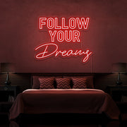 red follow your dreams neon sign hanging on bedroom wall