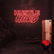 red hustle hard neon sign hanging on gym wall