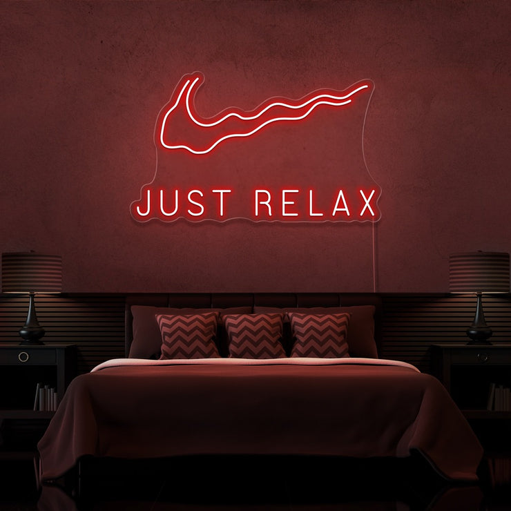 red just relax neon sign hanging on bedroom wall