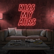 red kiss my airs neon sign hanging on living room wall