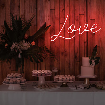 red love neon sign hanging on timber wall above dessert table