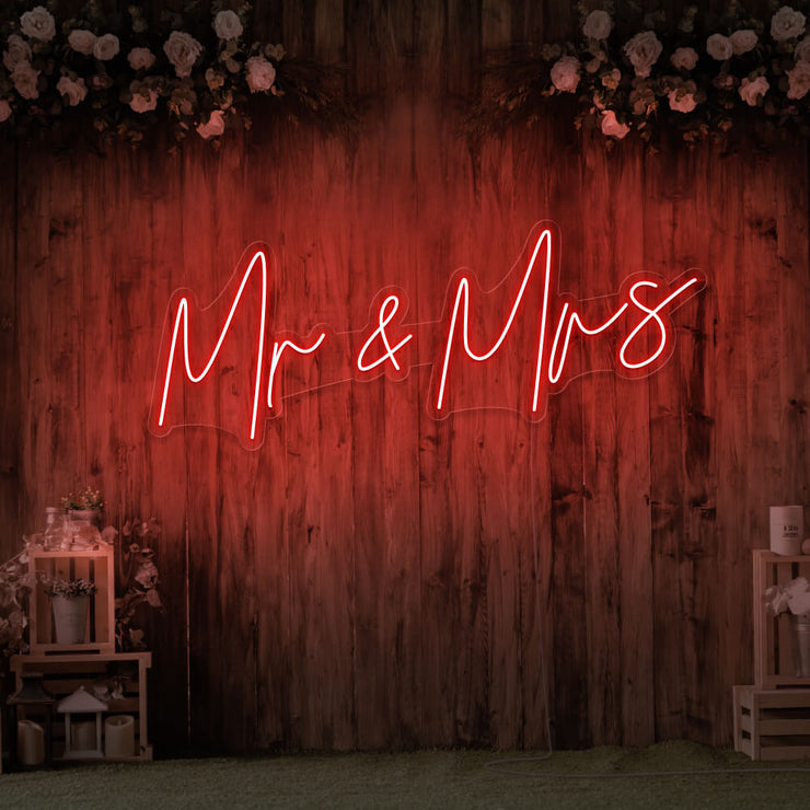 red mr and mrs neon sign hanging on wall with flowers