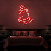 red praying hands neon sign hanging on bedroom wall
