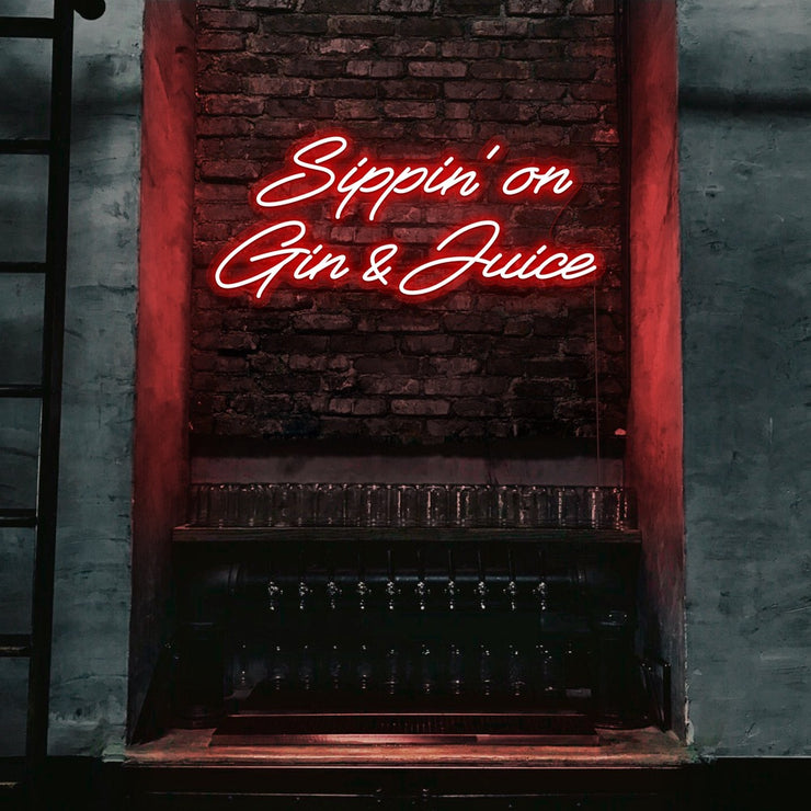 red sippin on gin and juice neon sign hanging on bar wall