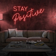 red stay positive neon sign hanging on living room wall