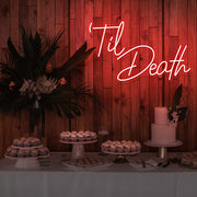 red til death neon sign hanging on timber wall above dessert table